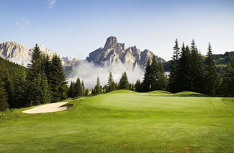 Saftig grüner Golfplatz vor einer dramatischen Bergkulisse in den Dolomiten bei Corvara.