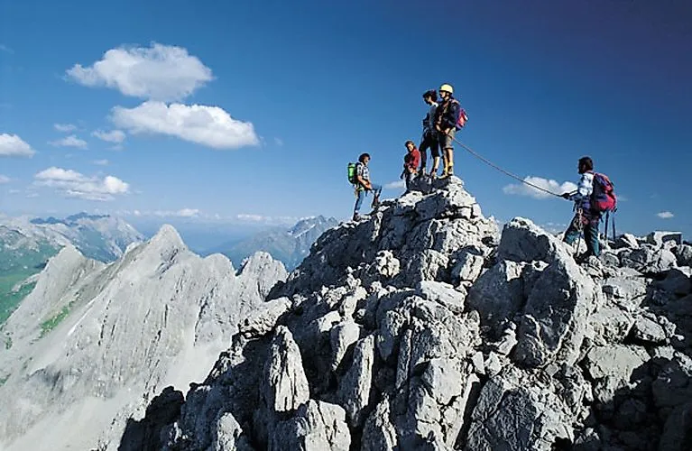Un grupo sube a una cumbre rocosa cerca de St. Anton am Arlberg con vistas a la montaña