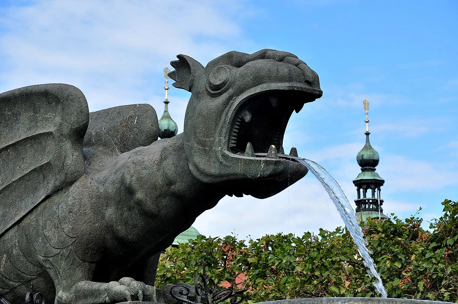 Lindwurmbrunnen in Klagenfurt with water jet and towers in the background