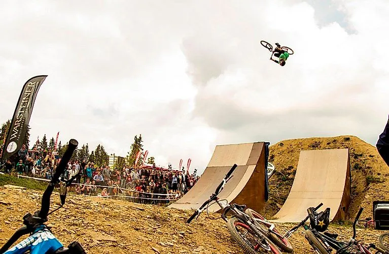 Mountainbiker springt spektakulär über Rampe bei Event in der Bike Arena Sauerland in Winterberg vor Publikum