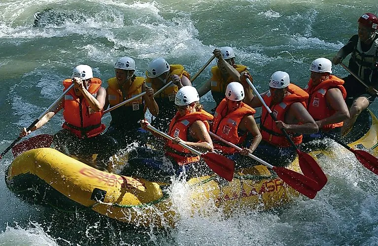 Skupinový rafting na rozbouřené řece ve Flachau v létě s helmami a záchrannými vestami.