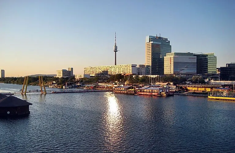Skyline von Wien mit Donauturm und moderner Donau City am Ufer der Donau bei Sonnenuntergang.