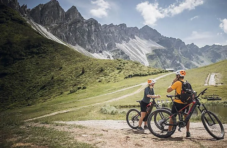 Zwei Mountainbiker pausieren vor beeindruckender Felskulisse nahe Gossensass in Südtirol.