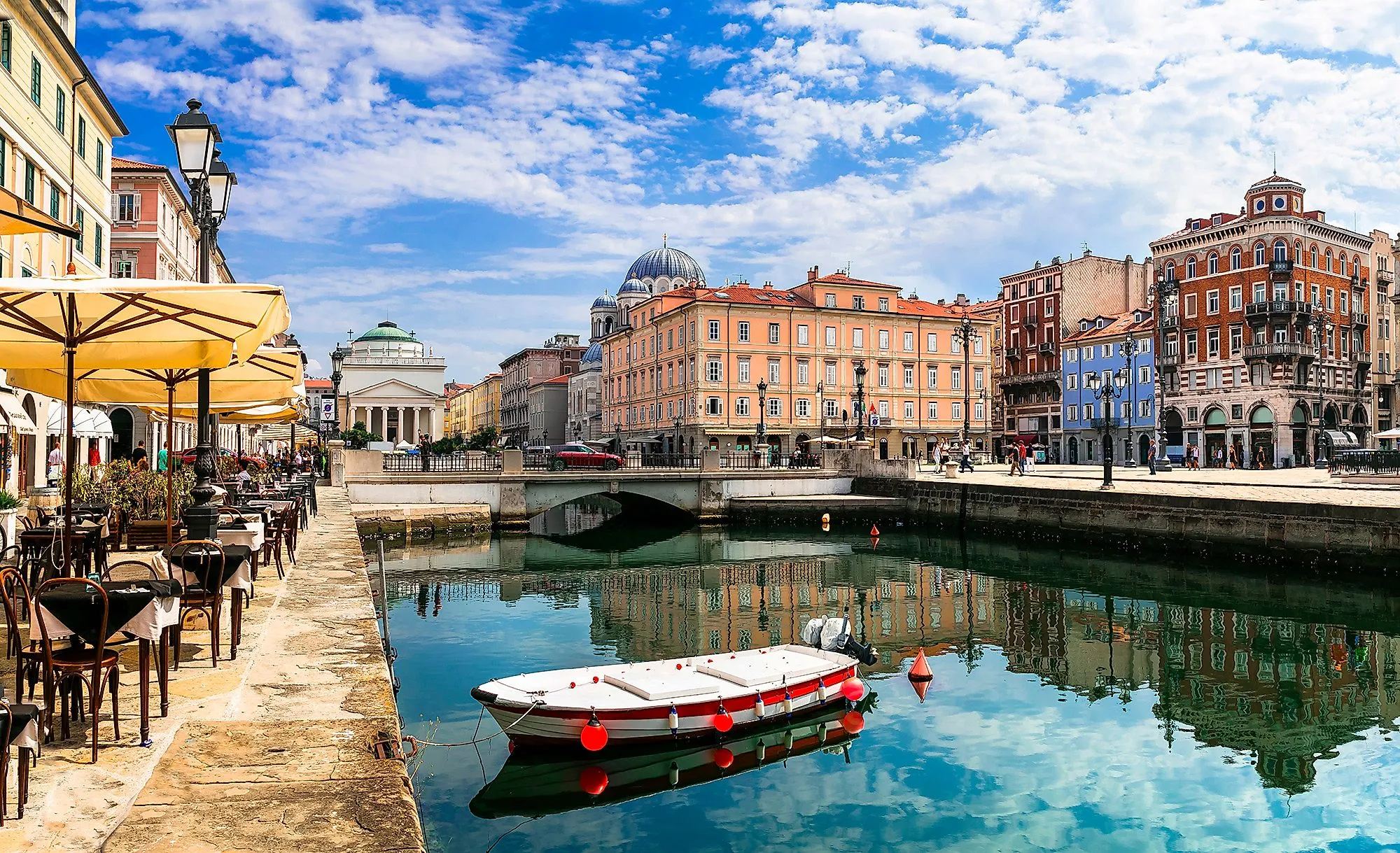 Kanal mit Boot, Cafés und pastellfarbenen Häusern in der Altstadt von Triest