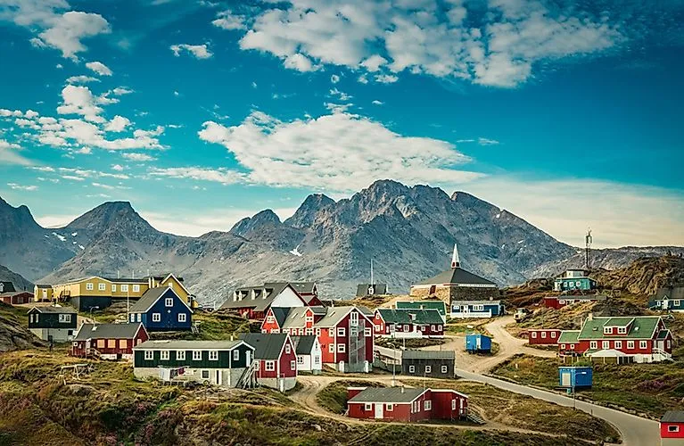Bunte Holzhäuser in Tasiilaq vor der majestätischer Bergkulisse Grönlands im Sommer