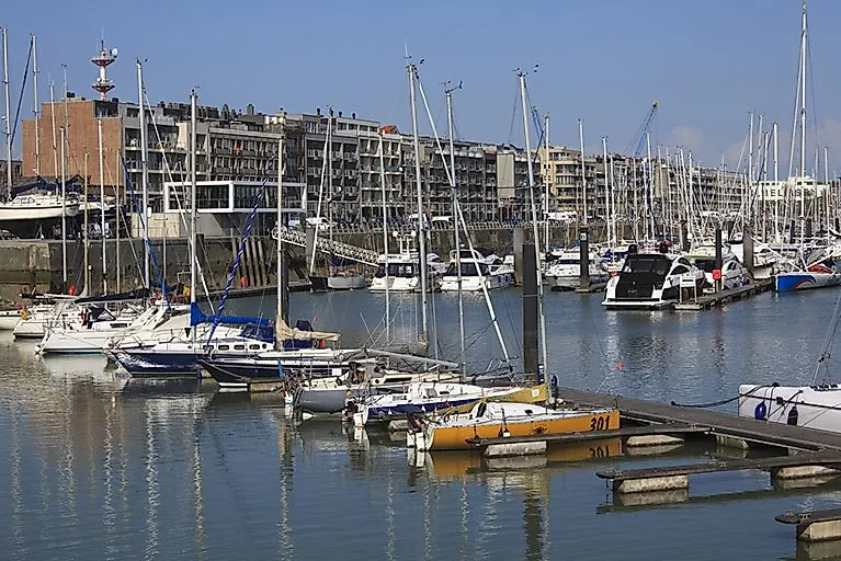 Blick auf den Jachthafen von Zeebrugge mit zahlreichen Segelbooten und Yachten, im Hintergrund moderne Wohnhäuser entlang der Kaimauer.