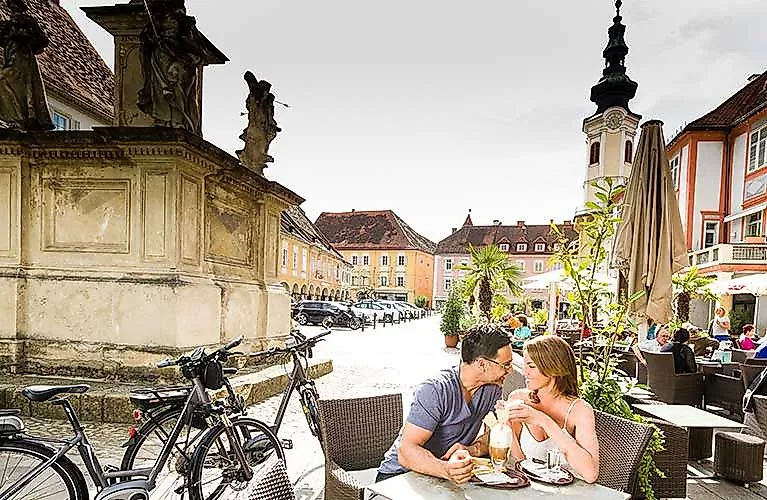 Paar genießt Kaffee auf dem historischen Hauptplatz von Bad Radkersburg in der Steiermark bei sommerlichem Wetter.