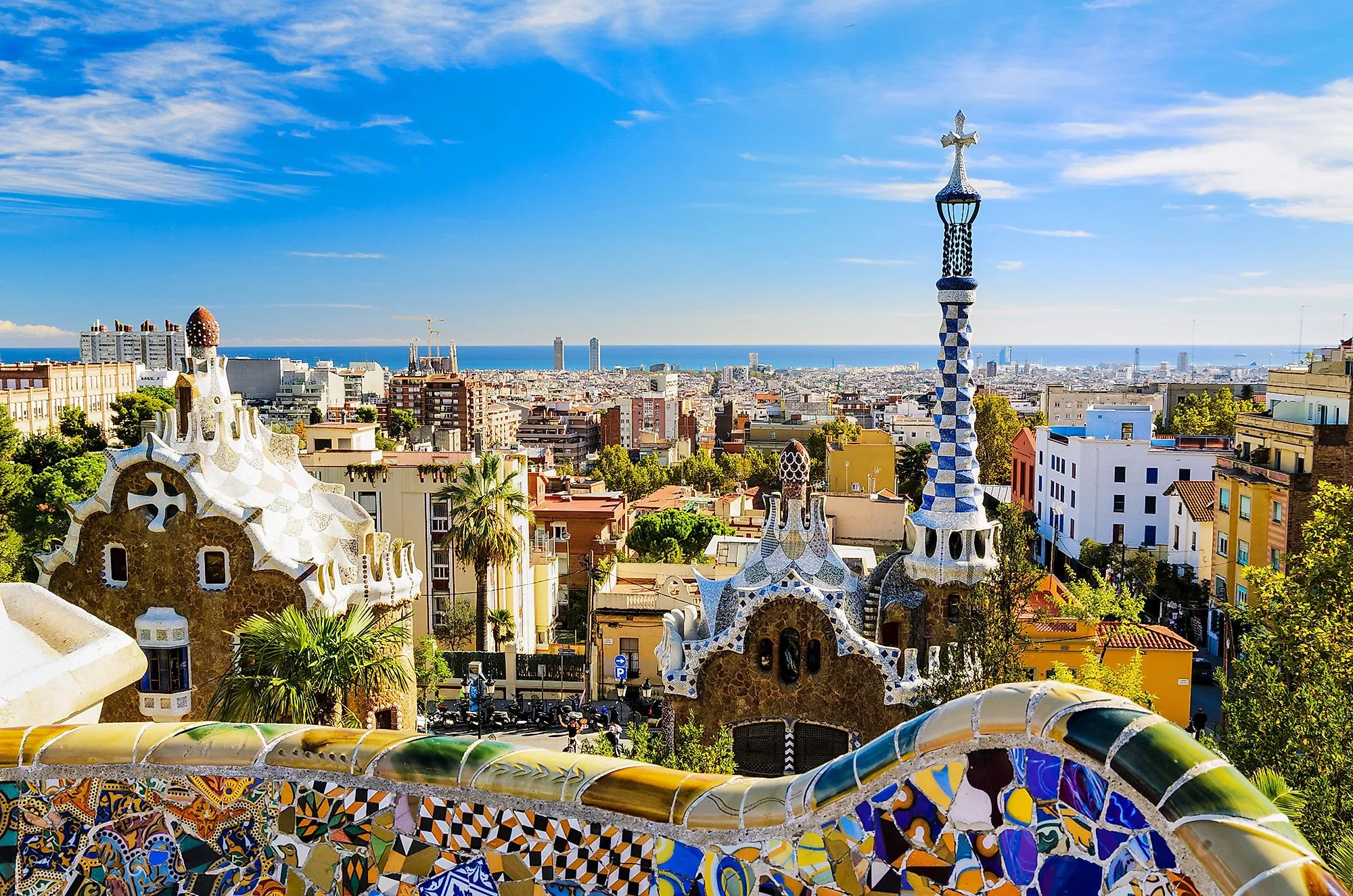 Park Güell in Barcelona mit farbenfrohen Mosaiken und Blick auf die Stadt bis zum Meer