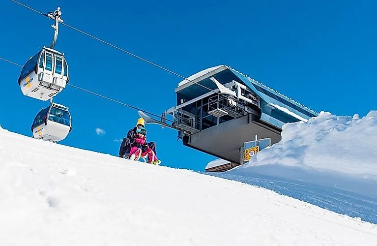 Bambini in slitta vicino alla stazione a monte Sonnenkopf nella Klostertal con la cabinovia sullo sfondo