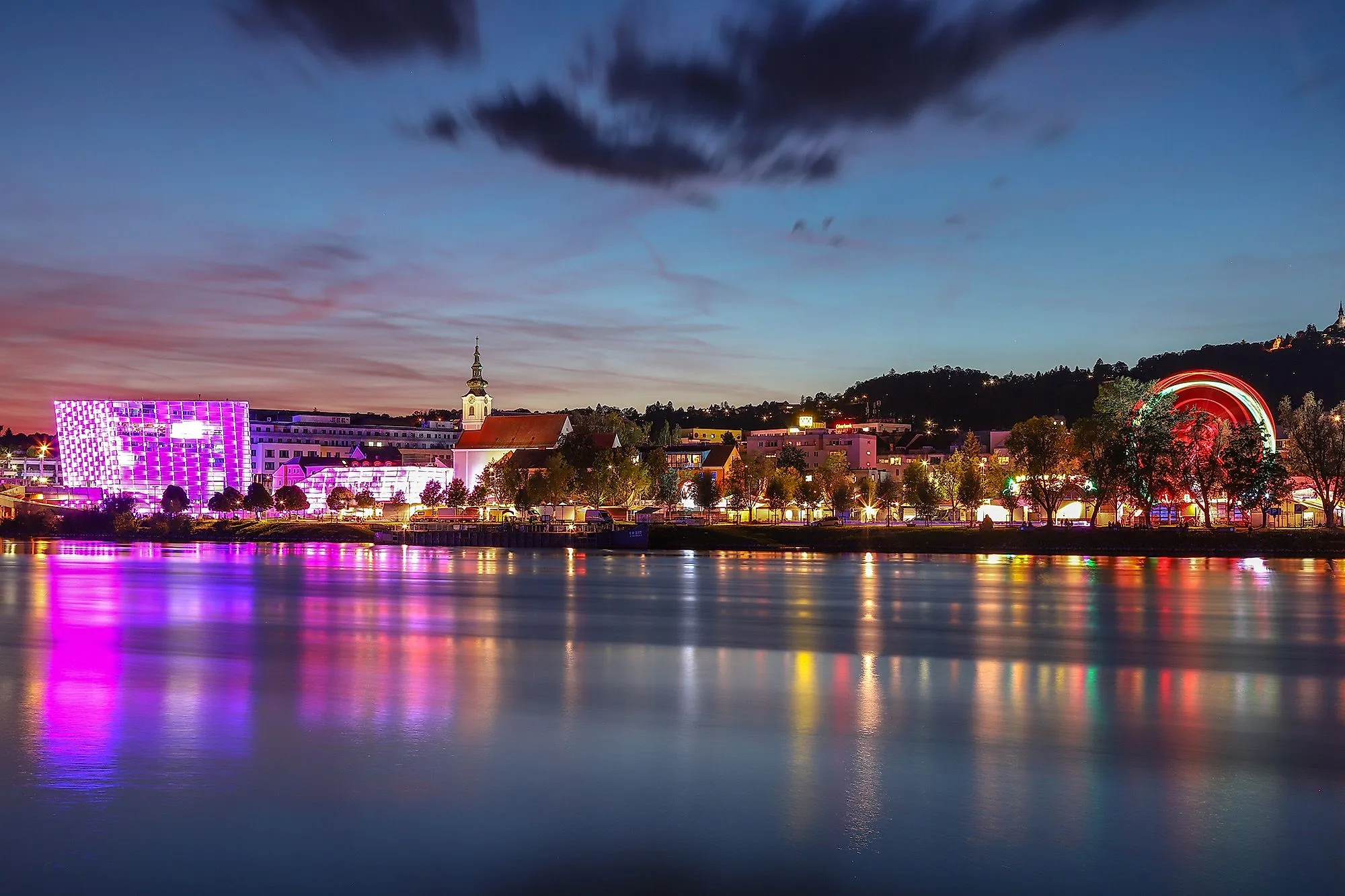 Nachtaufnahme von Linz mit Donau, leuchtendem Ars Electronica Center und Skyline