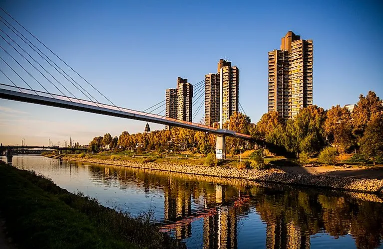 Neckarufer in Mannheim mit Collini-Center und moderner Brücke bei Sonnenuntergang