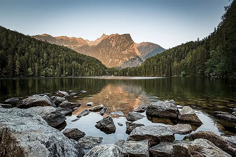 Spiegelung des Bergmassivs im ruhigen Piburger See bei Sonnenuntergang im Tiroler Ötztal.