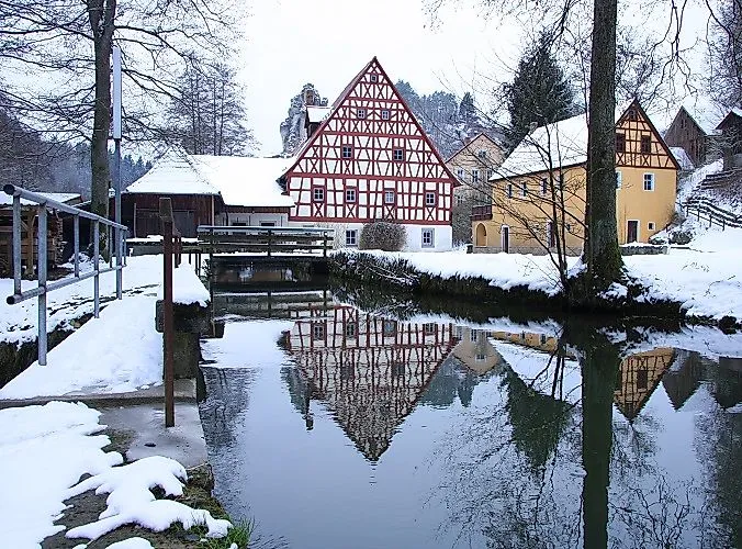 Fachwerkhäuser im Winter in Tüchersfeld bei Pottenstein mit Spiegelung im Wasser