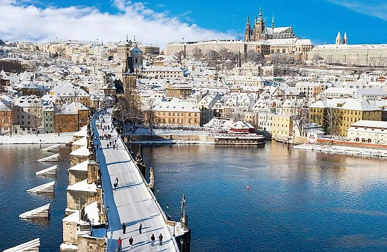 Puente de Carlos cubierto de nieve en Praga con vistas al Castillo de Praga y al casco antiguo en invierno