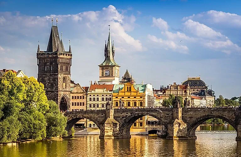 Vista veraniega del Puente de Carlos en Praga con la histórica torre del puente y las casas del casco antiguo bajo un cielo azul
