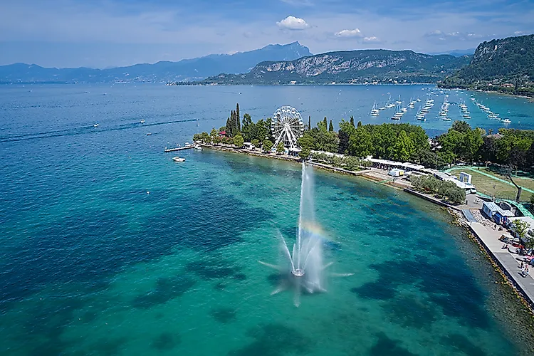 Peninsula on Lake Garda near Lazise with fountain, Ferris wheel and marina against a mountain backdrop