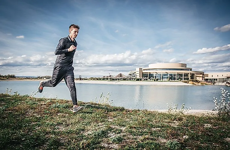 Jogger läuft am Seeufer vor der St. Martins Therme & Lodge im Burgenland