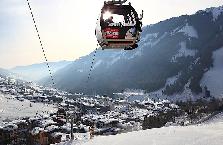 Winterliche Aussicht auf Saalbach mit schneebedeckten Dächern und der schwebenden Bernkogelbahn im Vordergrund.