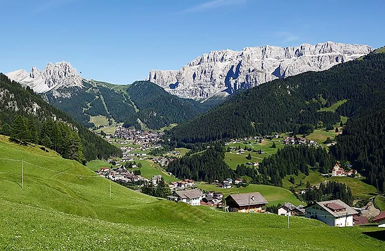 Wolkenstein im Sommer mit grünen Wiesen und Dolomiten im Hintergrund