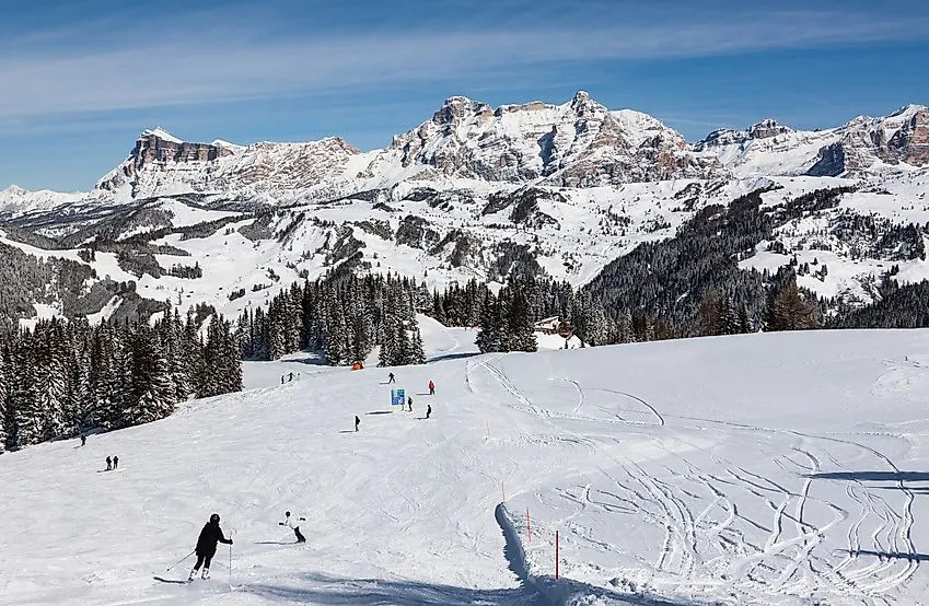 Skifahrer auf einer schneebedeckten Piste mit den majestätischen Dolomiten im Hintergrund bei Corvara.