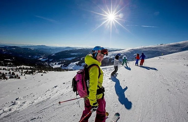 Skifahrerinnen und Skifahrer genießen sonnigen Wintertag auf der Skipiste im Lachtal mit weitem Panoramablick.