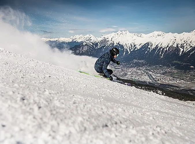 Skifahrer in Aktion mit Blick auf das verschneite Inntal und die Alpen am Glungezer in Tirol