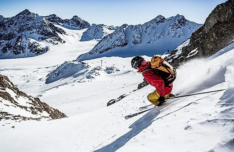 Skifahrer in roter Jacke fährt abseits der Piste am verschneiten Pitztaler Gletscher in Tirol