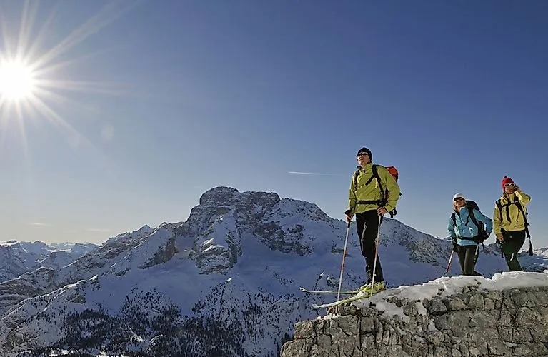 Drie skitoerers in Sesto met besneeuwde Dolomieten op de achtergrond in de zon