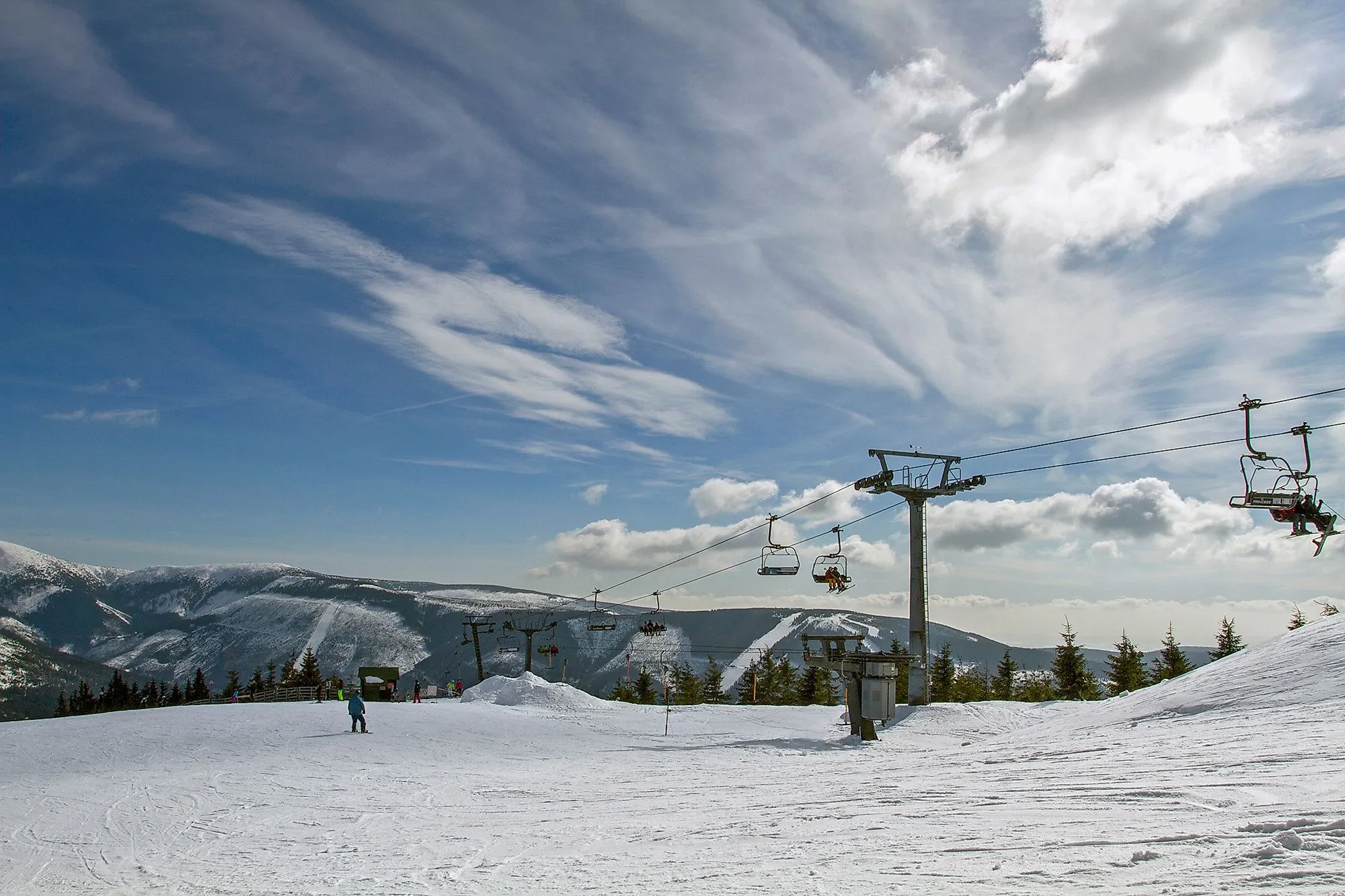 Skifahrer und Sessellift im Skigebiet Špindlerův Mlýn im Riesengebirge bei Sonnenschein.