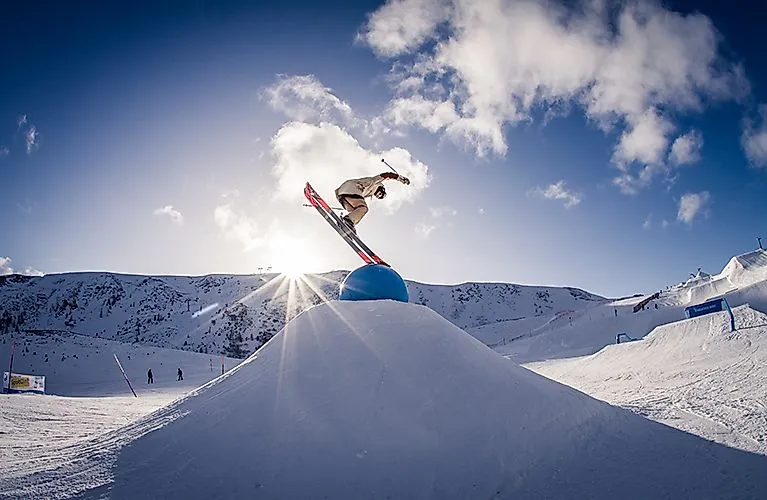 Snowboarder springt über Hindernis im Snowpark Turracher Höhe bei Sonnenschein