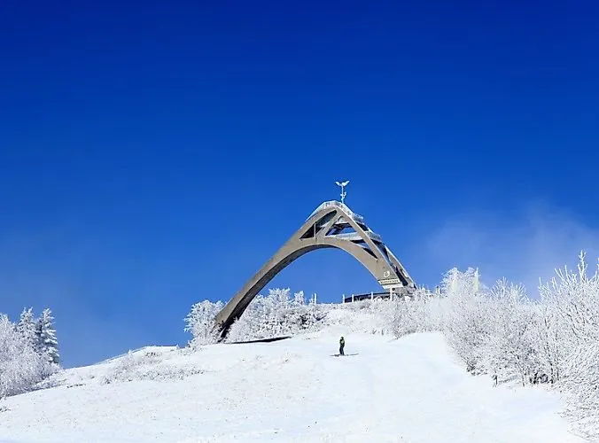 Schneebedeckte St. Georg Schanze in Winterberg mit Skifahrer und tiefblauem Himmel an einem klaren Wintertag