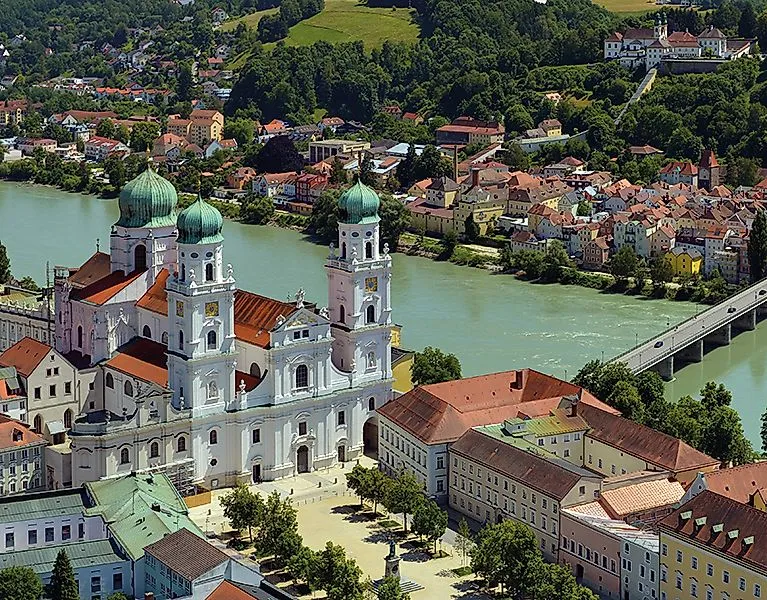 Cattedrale barocca di Santo Stefano a Passau con cupole a cipolla verde sulle rive del Danubio, circondata dal centro storico e dal verde paesaggio collinare