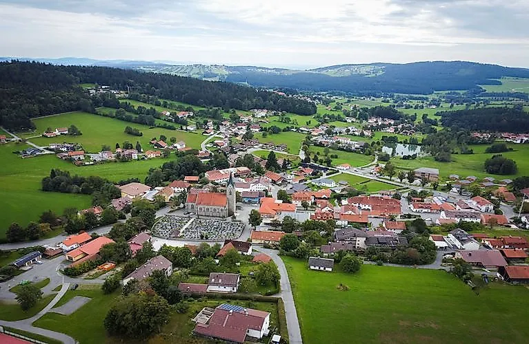 Sommerliche Ortsansicht von Neuschönau im Bayerischen Wald mit Blick auf grüne Hügel und traditionelle Dächer