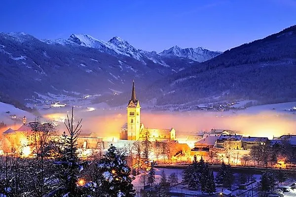 Winter town view of Radstadt with a glowing church and snow-covered mountains.