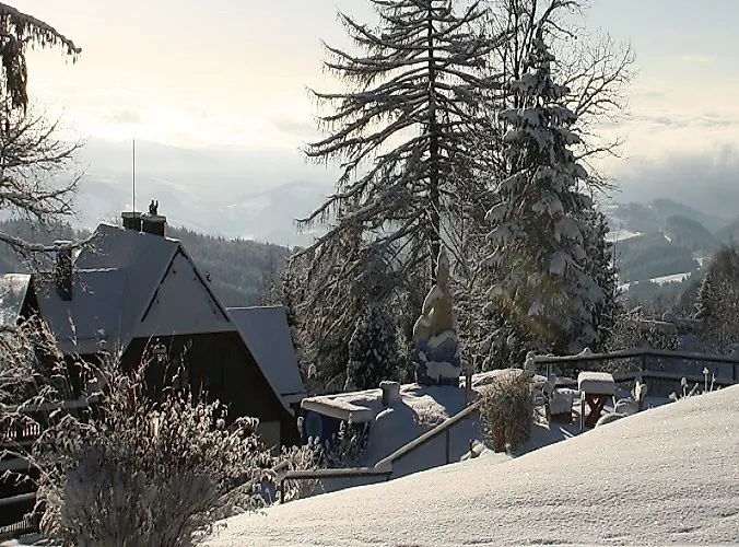 Verschneite Winterlandschaft in Mönichkirchen mit gemütlichen Hütten, schneebedeckten Bäumen und Fernblick ins Tal.