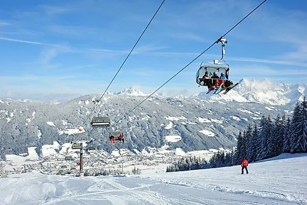 Skiers and chairlift on a snow-covered ski slope in Radstadt with a panoramic view of the Alps.