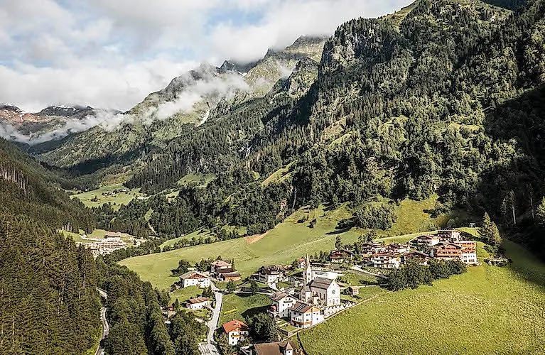 Sommerlicher Blick auf Gossensass mit Kirche, eingebettet in die Südtiroler Berglandschaft.
