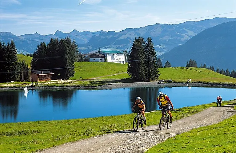 Radfahrer auf einem Sommertrail mit Bergblick und See bei Ellmau in der Region Wilder Kaiser.
