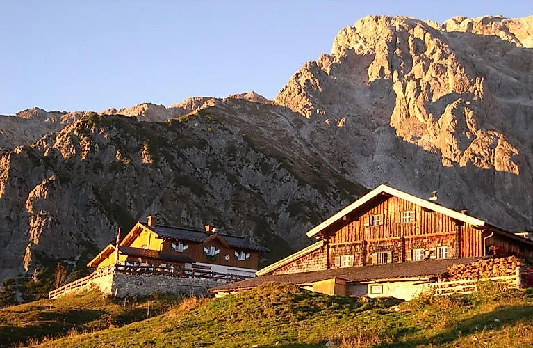 Zwei Berghütten vor imposanter Felskulisse am Hochkönig im goldenen Licht eines Sommerabends