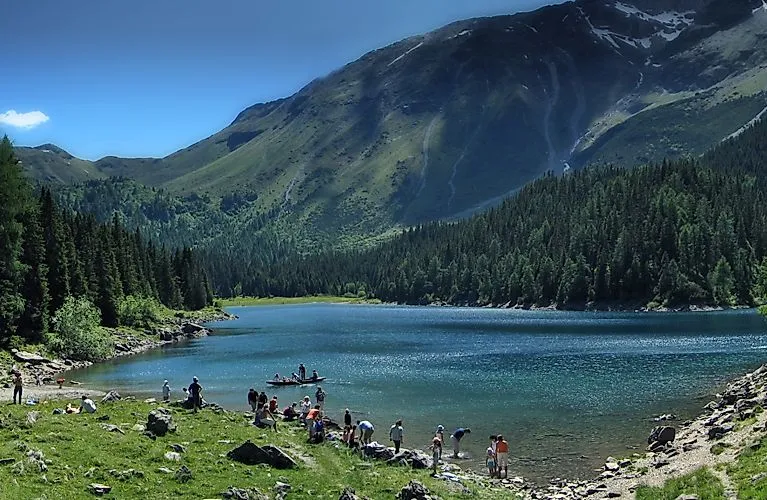 Menschen genießen einen Sommertag am idyllischen Bergsee bei Steinach in Tirol, umgeben von grüner Berglandschaft.