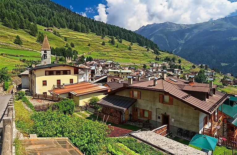 Blick auf Pejo im Sommer mit Kirche, Bergdorf und grüner Terrassenlandschaft im Val di Sole